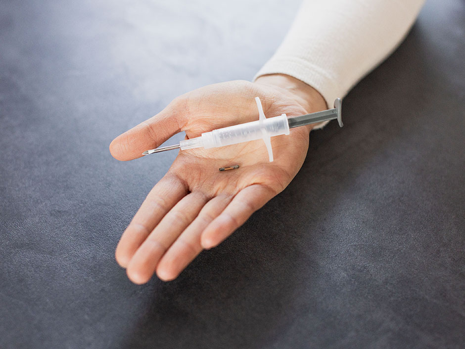 Hand zeigt Transponder und Injektionsspritze