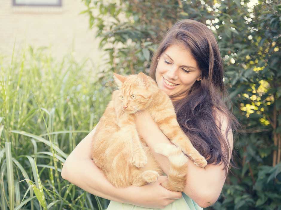 Eine Frau hält eine rote Katze im Arm. 