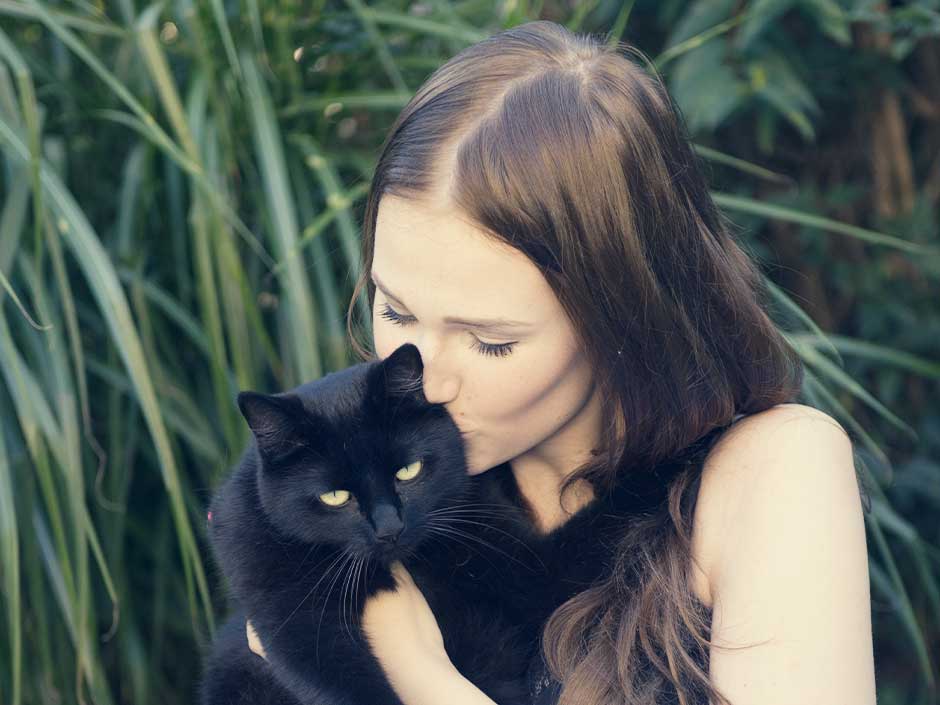 Eine Frau hält eine schwarze Katze auf dem Arm.